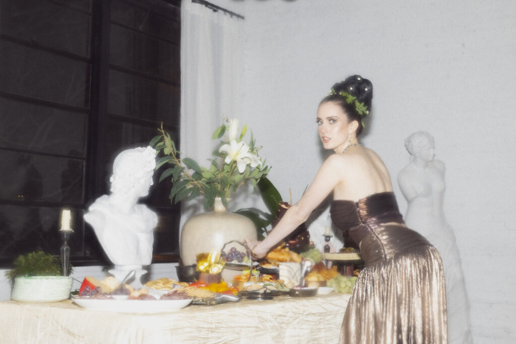 a woman dressed as a greek goddess leans over a table at a wicker park chicago venue