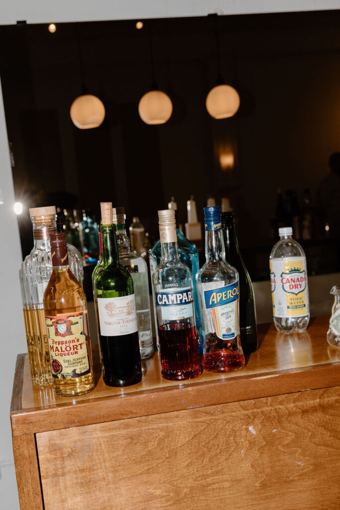 BYOB bar setup with Campari, Aperol, Malort and wine bottles on a wood bar at Le Loft Chicago